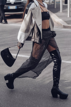 Milan, Italy - February, 24: Street style, woman wearing yellow shiny satin transparent dress, a black long coat, a black grained leather handbag and black ankle boots.のeditorial素材