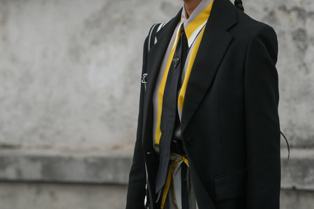 Milan, Italy - February, 24: Street style, woman wearing yellow shiny satin transparent dress, a black long coat, a black grained leather handbag and black ankle boots.のeditorial素材