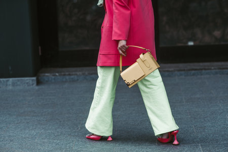 Milan, Italy - February, 24: Street style, woman wearing yellow bag, pink jacket, green pants and pink shoes.のeditorial素材