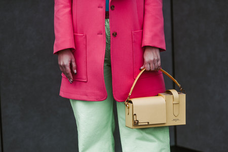 Milan, Italy - February, 24: Street style, woman wearing yellow bag, pink jacket and green pants.のeditorial素材