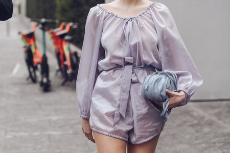 Milan, Italy - February, 24: Street style, woman wearing purple jumpsuit, a pale purple shoulder bag, white shiny leather crocodile high boots.のeditorial素材