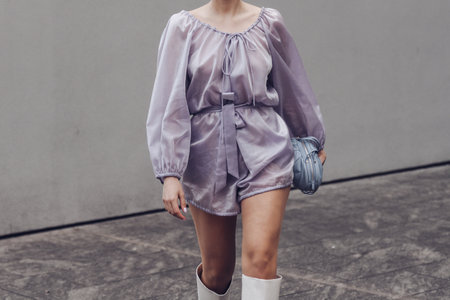 Milan, Italy - February, 24: Street style, woman wearing purple jumpsuit, a pale purple shoulder bag, white shiny leather crocodile high boots.のeditorial素材