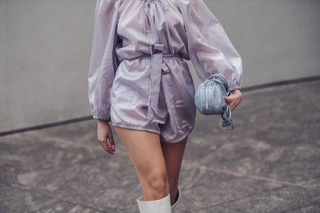 Milan, Italy - February, 24: Street style, woman wearing purple jumpsuit, a pale purple shoulder bag, white shiny leather crocodile high boots.のeditorial素材