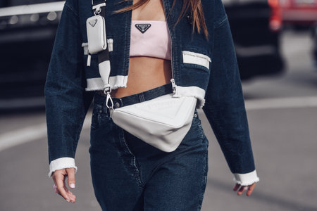 Milan, Italy - February, 24: Street style, woman wearing Prada outfit: pale pink cropped top from Prada, white leather cross body bag, navy blue denim jacket.のeditorial素材