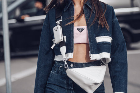 Milan, Italy - February, 24: Street style, woman wearing Prada outfit: pale pink cropped top from Prada, white leather cross body bag, navy blue denim jacket.のeditorial素材