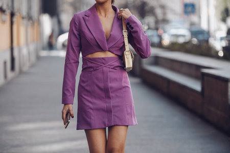 Milan, Italy - February 25, 2022: Crop anonymous female in purple outfit with high heels walking on street.のeditorial素材