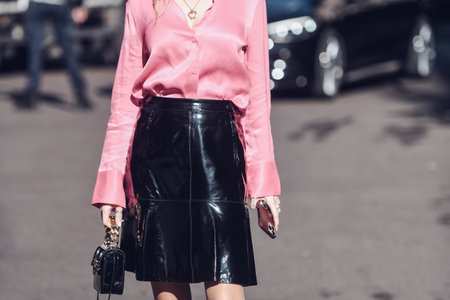 Milan, Italy - February 26, 2022: Female wearing a pink blouse, shiny black leather skirt, black shiny handbag and pink shoes.のeditorial素材