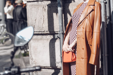 Milan, Italy - February 25, 2022: Crop female in checkered dress and brown leather coat with red handbag in Milan.のeditorial素材