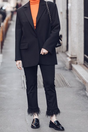 Milan, Italy - February 25, 2022: Woman in black suit and orange turtleneck wearing leather moccasins.のeditorial素材