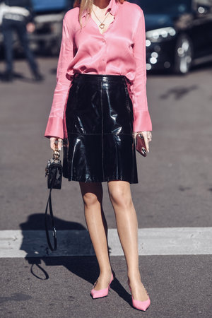 Milan, Italy - February 26, 2022: Female wearing a pink blouse, shiny black leather skirt, black shiny handbag and pink shoes.のeditorial素材