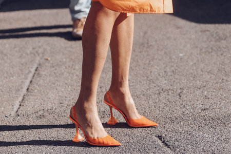 Milan, Italy - February 25, 2022: Woman in orange dress and high heeled shoes.のeditorial素材