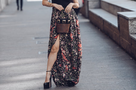 Milan, Italy - February 25, 2022: Woman wearing a v-neck black shirt, ornamental brown skirt and brown handbag.のeditorial素材