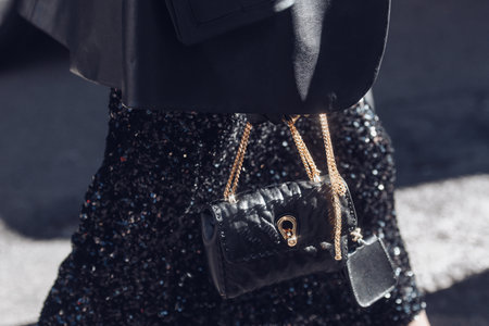 Milan, Italy - February 26, 2022: Female wearing a black glitter dress and black purse white golden lace.のeditorial素材
