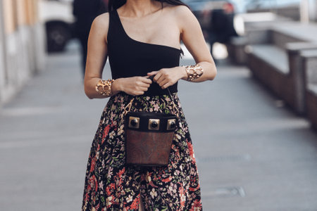 Milan, Italy - February 25, 2022: Woman wearing a v-neck black shirt, ornamental brown skirt and brown handbag.のeditorial素材