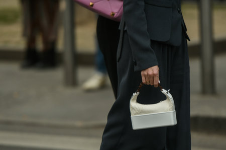Milan, Italy - February 24, 2022: Woman walking on street wearing black jacket and wide leg pants with white handbag.のeditorial素材