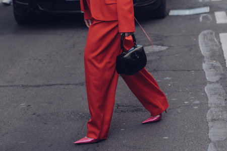 Milan, Italy - February 25, 2022: Female wearing a red fancy suit, black handbag and pink elegant shoes.のeditorial素材
