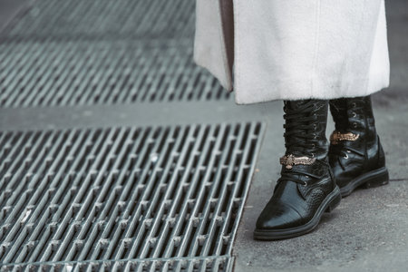 Milan, Italy - February 24, 2022: Woman wearing trendy beige coat and black leather boots with laces.のeditorial素材