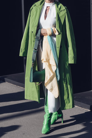 Milan, Italy - February 25, 2022: Female wearing a green coat, white dress, matching green bag and green high heels boots.のeditorial素材