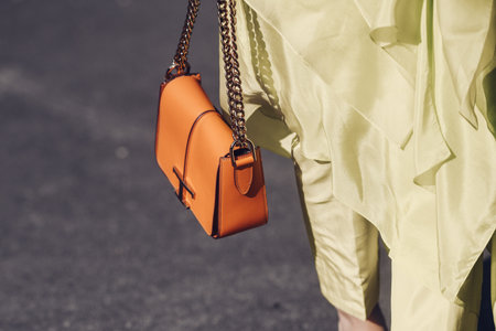 Milan, Italy - February 24, 2022: From above of Woman in yellow unusual outfit with brown leather handbag.のeditorial素材