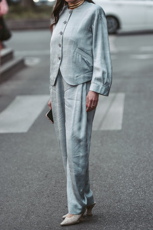 Milan, Italy - February 24, 2022: Woman in beige jacket tie and black trousers standing with handbag and hand in pocket.のeditorial素材