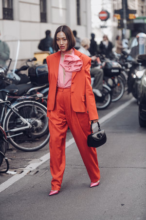 Milan, Italy - February 25, 2022: Female wearing a red fancy suit, black handbag and pink elegant shoes.のeditorial素材