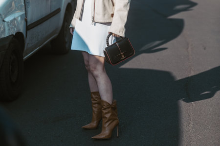 Milan, Italy - February 24, 2022: Man in beige trousers and quilted overshirt with brown leather pockets walking with female in skirt and knitted sweater with horizontal linesのeditorial素材