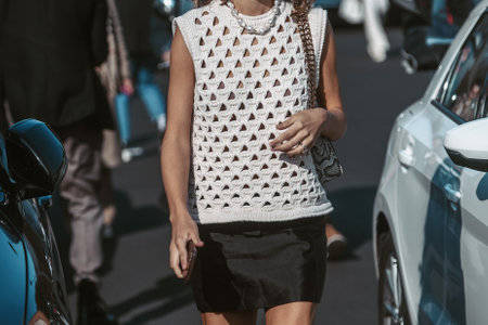 Milan, Italy - February 24, 2022: Woman in white crochet sleeveless top and black skirt with necklace and handbag.のeditorial素材