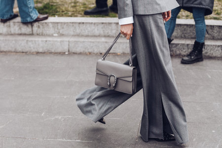 Milan, Italy - February 24, 2022: Woman in gray jacket and wide leg pants with chain purse.のeditorial素材