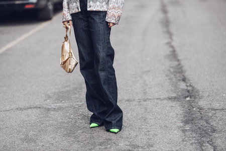 Milan, Italy - February 24, 2022: Woman wearing long dark jeans light green high heels and ornamental jacket.のeditorial素材