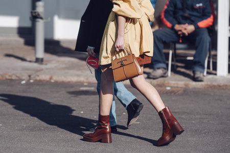 Milan, Italy - February 24, 2022: Woman in stylish light coat dress and leather brown boots.のeditorial素材