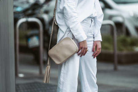 Milan, Italy - February 24, 2022: Woman in white stylish sweater and trousers with beige handbag.のeditorial素材
