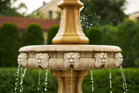 Fountain with little angels and demons antique little waterfall in the garden falling drops close-upの写真素材