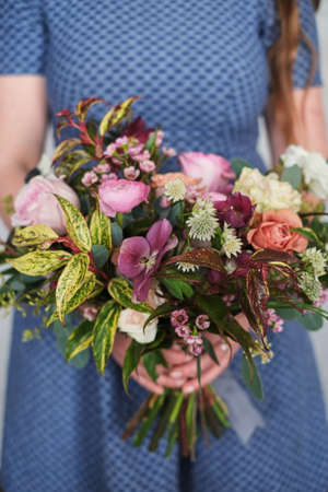 Girl holding colorful wedding bouquet against blue dressの写真素材