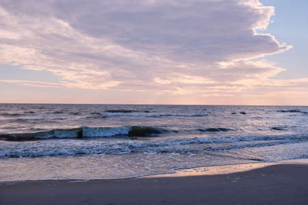 Golden sunrise behind the clouds, pink sky and calm sea. Seascape in the eveningの写真素材