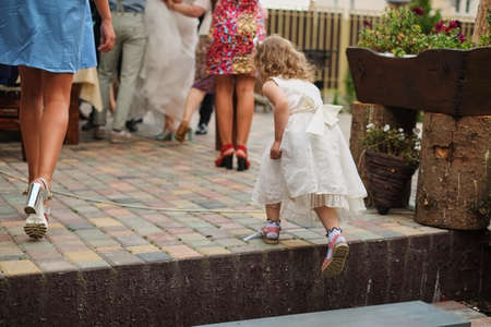 beautiful little girl with long hair in elegant dress run in beautiful place at the weddingの写真素材