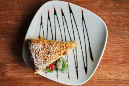 a piece of poured honey cake with chocolate topping on a plate, top view, set.の写真素材