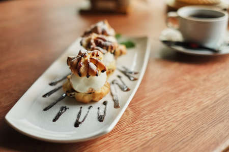 Choux cream on a narrow white plate side view wooden table backgroundの写真素材