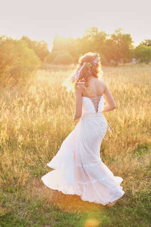 Young girl in a white dress in the meadow. Woman in a beautiful long dress posing in the garden.の写真素材