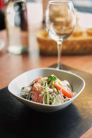 vegetable salad with cabbage tomatoes, cucumbers, onions, side view on a caffe backgroundの写真素材