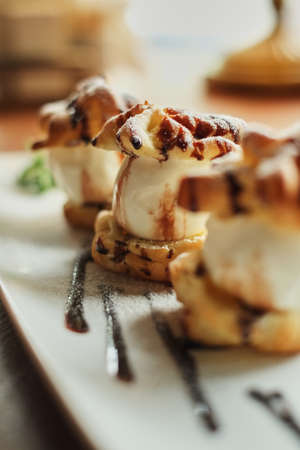 Choux cream on a narrow white plate side view wooden table backgroundの写真素材