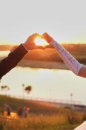 wedding couple hands touching fingers in the shape . Bright light of sun on background.の写真素材