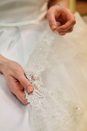 Bride's hand touching details of her wedding dress. Simple french manicureの写真素材