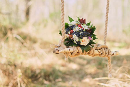 wedding bouquet of dark berries, roses outdoors on the decorated swingの写真素材