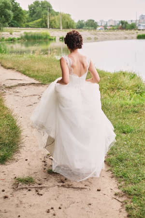 Bride goes through the forest holding a magnificent dress, wedding conceptの写真素材