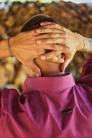 young man from the back, stands with arms folded behind his head, hands in the castle, looks at the...