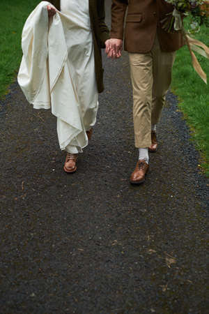 feet of bride and groom on the autumn road.の写真素材