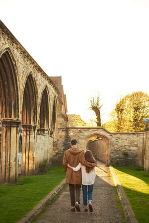 Rear view of a silhouette of a loving couple, hugging while visiting a destination city, walking along the old street of English cityの写真素材