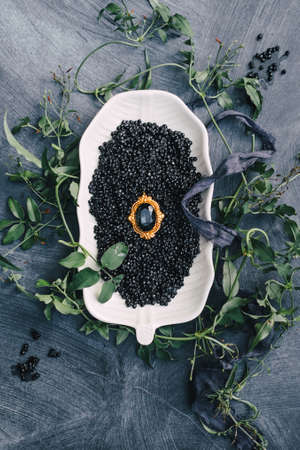 Golden rings in the sun glow on the table. Wedding details with dark black caviar on a dark...