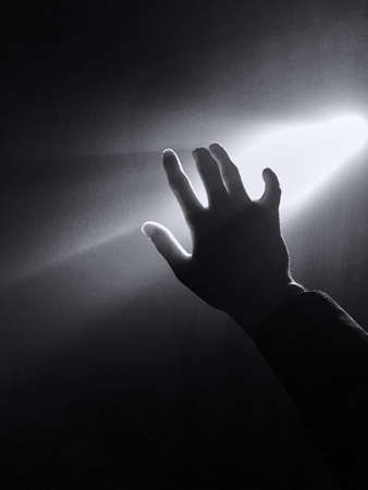 dark silhouette of human male hand with fingers in spotlight or backlight light with gesture on...