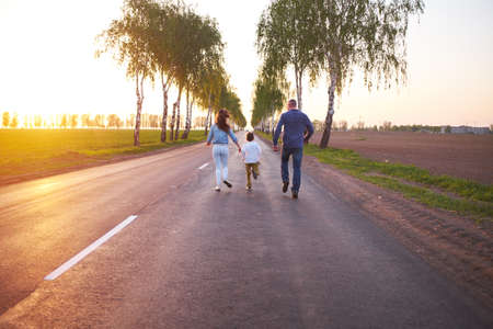 Happy family dad mom and son playing outdoors on the road near the field, watching the beautiful...
